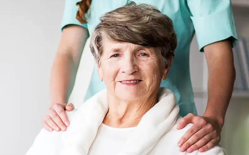 An elderly woman with a hand on her shoulder